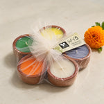Set of five colorful aromatic diyas arranged in a floral pattern and wrapped in elegant net packaging with a marigold flower.