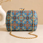 Azure Heritage Clutch with blue heritage-inspired woven pattern, gold chain strap, and crystal clasp
