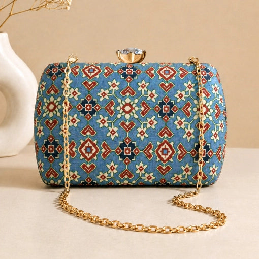 Azure Heritage Clutch with blue heritage-inspired woven pattern, gold chain strap, and crystal clasp