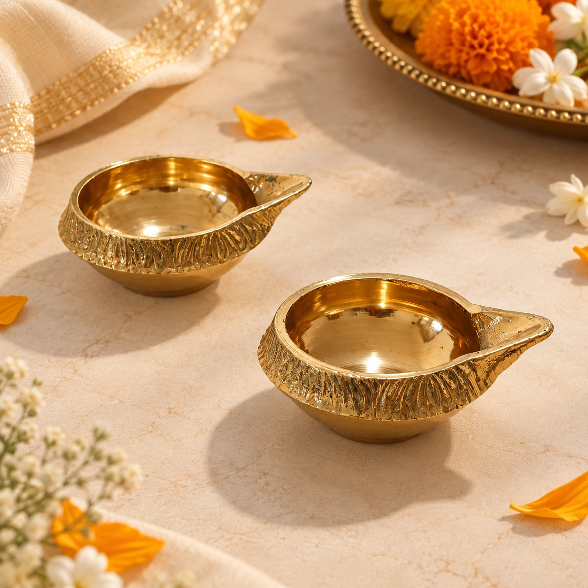 Traditional brass diya with an elegant carved design displayed on a festive backdrop with marigold flowers.