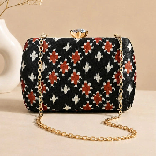 Ebony Ikat Clutch featuring black Ikat-inspired woven pattern, gold chain strap, and crystal clasp