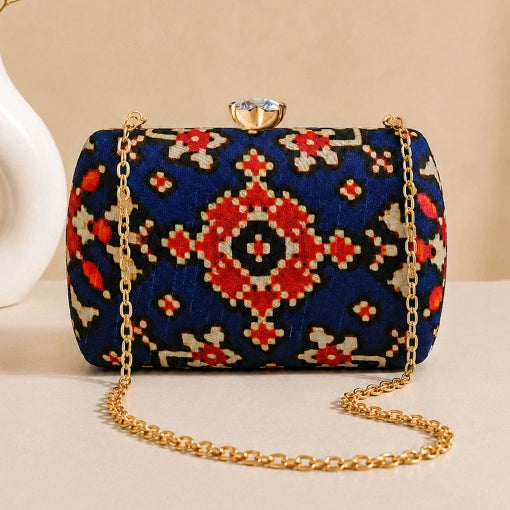 Midnight Ikat Clutch featuring navy blue Ikat-inspired woven pattern, gold chain strap, and crystal clasp