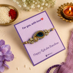 Regal Peacock Rakhi featuring a peacock-inspired centerpiece with blue stones and crystal embellishments, elegantly displayed on a premium Raksha Bandhan greeting card with festive décor.