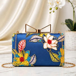 Sapphire Bloom Printed Highlight Clutch featuring floral artwork on a sapphire blue base, gold-tone frame clasp, detachable chain, and premium evening bag design.