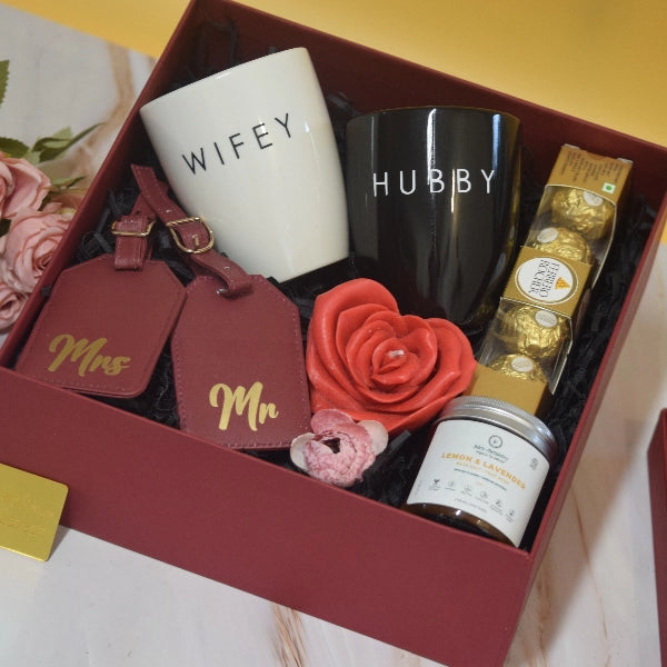 The Forever Together Hamper featuring Hubby and Wifey ceramic mugs, personalized Mr. & Mrs. luggage tags, Ferrero Rocher chocolates, lemon and lavender bath salt, decorative rose, and premium luxury gift packaging by YelloWraps.