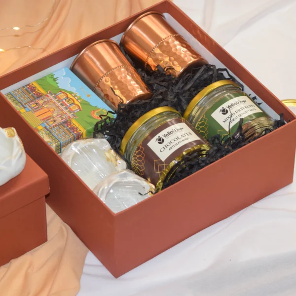 Diwali Glow Hamper with lotus candle holders, dry fruits, chocolates, copper glass set, and incense cones.