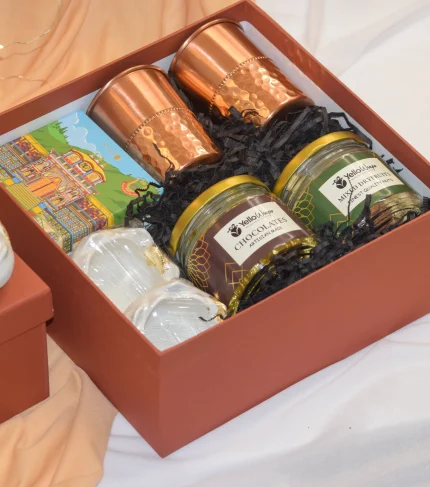 Diwali Glow Hamper with lotus candle holders, dry fruits, chocolates, copper glass set, and incense cones.